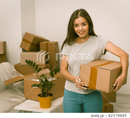 Beautiful hispanic female standing with box in new home 62579605