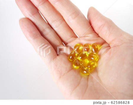 黄色いビタミン剤と手の写真素材