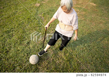 Asian senior woman with walking stick,playing with old football,healthy female elderly is kicking soccer ball,physical exercise,training leg muscles,body balance of old people,health care,good healthy 62594974