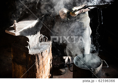 Blacksmith forging process - Cooling out an item in the bucket of cool water 62596366