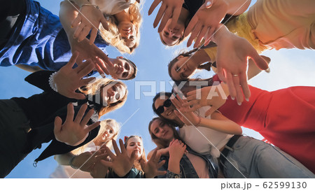 Happy friends connected in a ring together. View from the bottom. The concept of strong friendship. Happy friends connected in a ring together. View from the bottom. The concept of strong friendship. 62599130