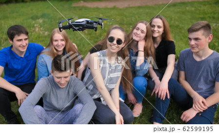Cheerful friends are watching the flight of the drone. 62599195