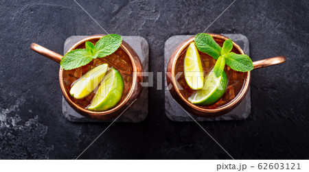Cold Moscow Mules cocktail with ginger beer, vodka, lime and mint. Grey stone background. Top view. Cold Moscow Mules cocktail with ginger beer, vodka, lime and mint. Grey stone background. Top view. 62603121