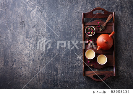 Green tea rose oolong in a clay tea cup and tea pot. Dark stone background. Top view. Copy space. 62603152