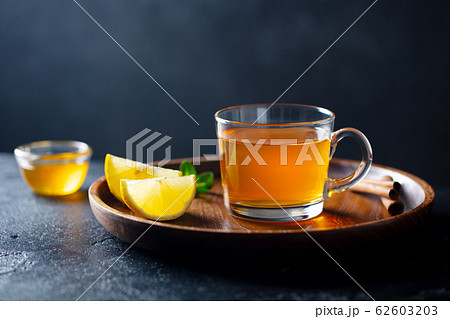 Tea cup with honey and lemon on wooden tray. Grey background. Copy space. 62603203