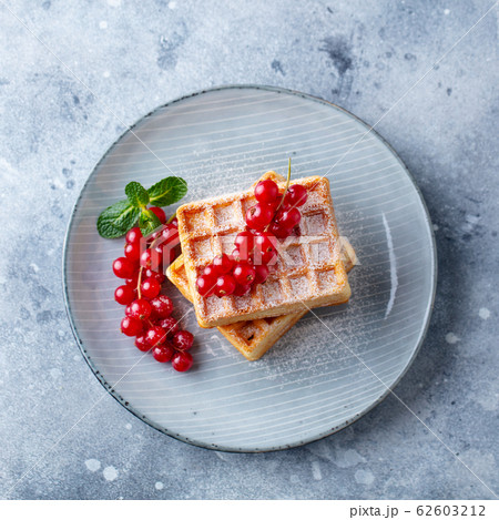 Belgian waffles with fresh red currant berries. Grey background. Top view. 62603212