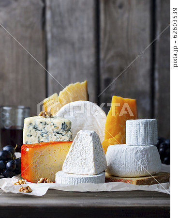Cheese assortment: blue cheese, hard cheese, soft cheese on a parchment paper. Wooden background. Copy space. Cheese assortment: blue cheese, hard cheese, soft cheese on a parchment paper. Wooden background. Copy space. 62603539