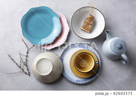 Ceramic crockery tableware, plates, bowls, cup and teapot on grey stone background. Top view. Ceramic crockery tableware, plates, bowls, cup and teapot on grey stone background. Top view. 62603575