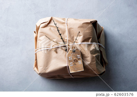 Gift box wrapped in craft paper with a rustic twine and decorations. Grey background. Top view. Copy space. Gift box wrapped in craft paper with a rustic twine and decorations. Grey background. Top view. Copy space. 62603576