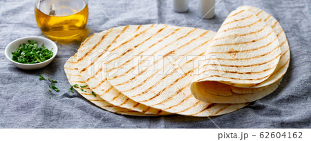 Tortillas, flat breads with olive oil on grey textile background. Close up. 62604162