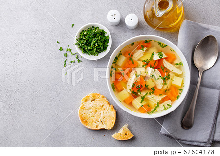 Chicken soup with vegetables in white bowl. Grey stone background. Copy space. Top view. 62604178