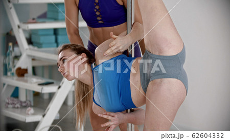 Young attractive plastic woman standing in leg split holding on the pole 62604332