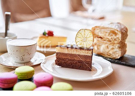 Chocolate sponge cake, with mousse, decorated with Orange slice and meringue. Breakfast in the cafe, morning coffee. on wooden table. 62605106