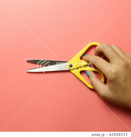 Scissors with hand on pink background Scissors with hand on pink background 62606555