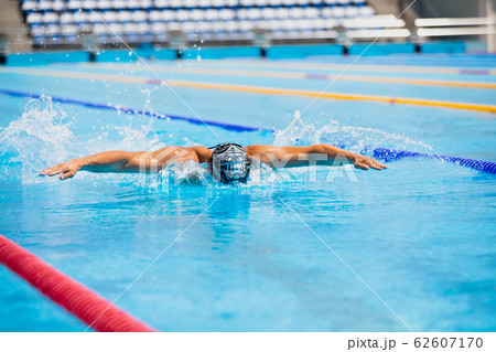Athletic man swimming in butterfly style in the swimming pool with clear blue water. Athletic man swimming in butterfly style in the swimming pool with clear blue water. 62607170
