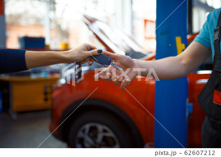 Female driver gives keys to worker in uniform Female driver gives keys to worker in uniform 62607212