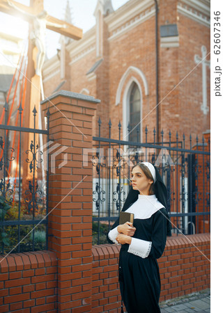 Young nun in a cassock, church on background 62607346