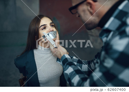 Maniac kidnapper taping his victim's mouth shut Maniac kidnapper taping his victim's mouth shut 62607400