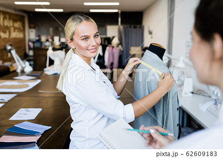 Young smiling blond seamstress looking at her colleague during conversation 62609183