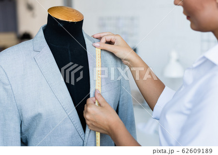 Young fashion designer with yellow tape measuring length of jacket collar 62609189