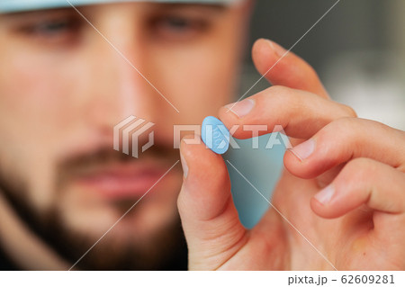 Close up of male doctor holding pill for men health Close up of male doctor holding pill for men health 62609281