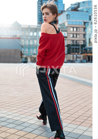 Urban Style. Young stylish woman walking outdoors hands in pockets back view pensive full body shot Urban Style. Young stylish woman walking outdoors hands in pockets back view pensive full body shot 62610536