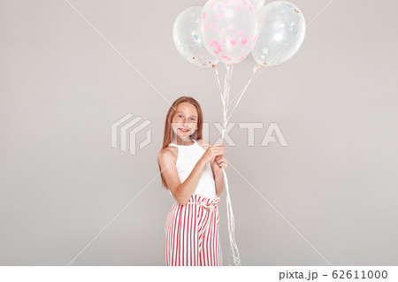 Inclusive Beauty. Girl with freckles standing isolated on grey holding balloons posing smiling happy Inclusive Beauty. Girl with freckles standing isolated on grey holding balloons posing smiling happy 62611000