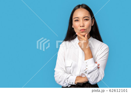Freestyle. Young woman wearing shirt and skirt standing isolated on blue touching chin thoughtful 62612101