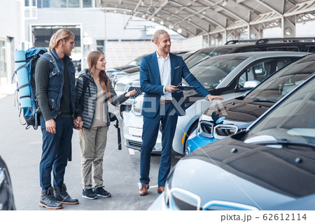 Young adult man and woman choosing rental car for travel Young adult man and woman choosing rental car for travel 62612114