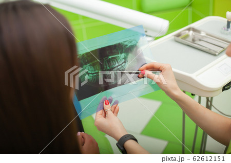 Dentist in dental office talking with female patient and preparing for treatment Dentist in dental office talking with female patient and preparing for treatment 62612151