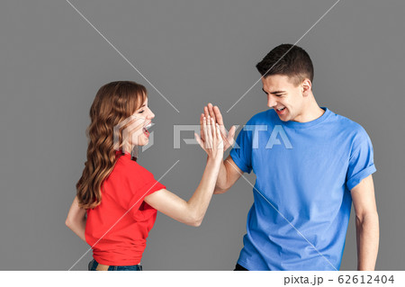 Freestyle. Young couple standing isolated on grey giving high five playful 62612404