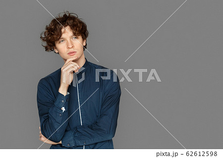 Copy Space for Text or Product. Teenager boy standing isolated on grey touching chin pensive Copy Space for Text or Product. Teenager boy standing isolated on grey touching chin pensive 62612598