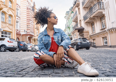 Outdoors Leisure. Young girl in denim jacket and sunglasses siting in road looking aside confident Outdoors Leisure. Young girl in denim jacket and sunglasses siting in road looking aside confident 62613051