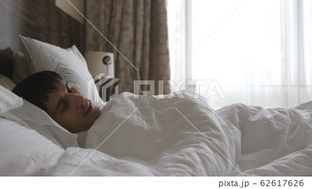 Handsome young man happily sleeping in white bed Handsome young man happily sleeping in white bed 62617626