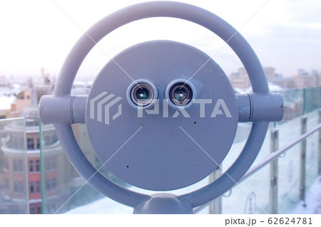 Binoculars on observation deck on roof of the building in the city in winter. 62624781