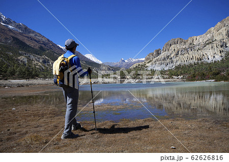 Man standing to look at view of lake with snow Man standing to look at view of lake with snow 62626816