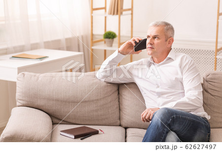 Senior man talking on mobile phone at his home 62627497