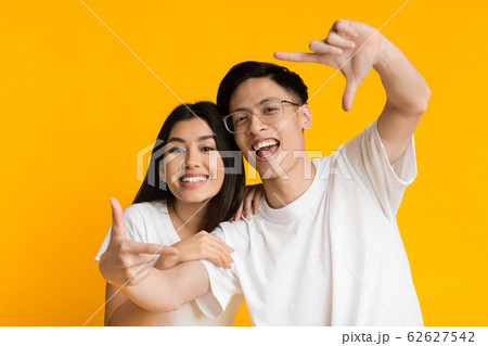 Young asian man and woman show frame sign with hands Young asian man and woman show frame sign with hands 62627542