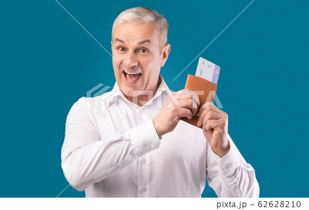 Excited man holding tickets and passport at studio Excited man holding tickets and passport at studio 62628210