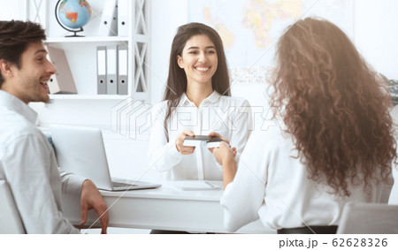 Female travel agent giving tickets to happy couple 62628326