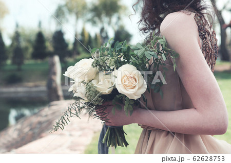 Woman in boho dress holding lush bouquet 62628753