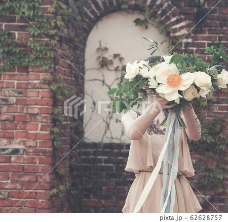 Woman in boho dress holding lush bouquet 62628757
