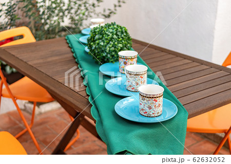 Wooden table with cups and plates at the backyard 62632052