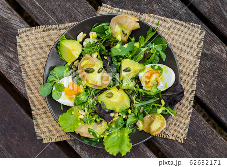 Salad with vegetables, eggs and greens on wooden table 62632171