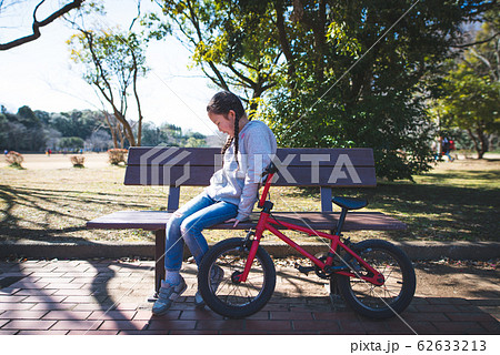 公園のベンチでのんびりする女の子の写真素材