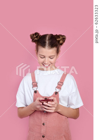 Beautiful teenager girl using smartphone on pink background 62633323