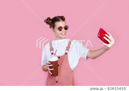 trendy stylish beautiful girl in white t-shirt and sunglasses while she makes selfie photo on her smartphone 62633450