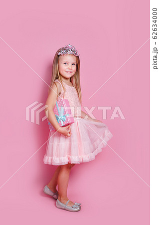 Little princess girl in crown holding gift box 62634000