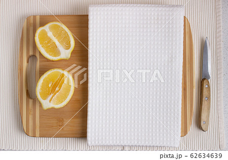White kitchen waffle towel on wooden cutting board with fresh lemons. Product design 62634639