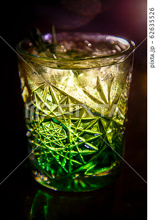 A green cocktail in an old fashion glass is on the bar A green cocktail in an old fashion glass is on the bar 62635526